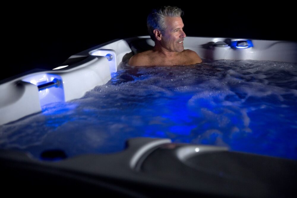 Man in Sundance® Spas 880™ Optima® - The Sundance® Spa Dealers at Great Bay Spa & Sauna serving New England explain the stress-relieving benefits of hydrotherapy.
