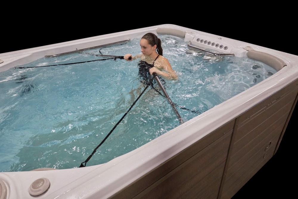 Woman rowing in a Hydropool Swim Spa - Great Bay Spa & Sauna explains the benefits of exercising in a swim spa.