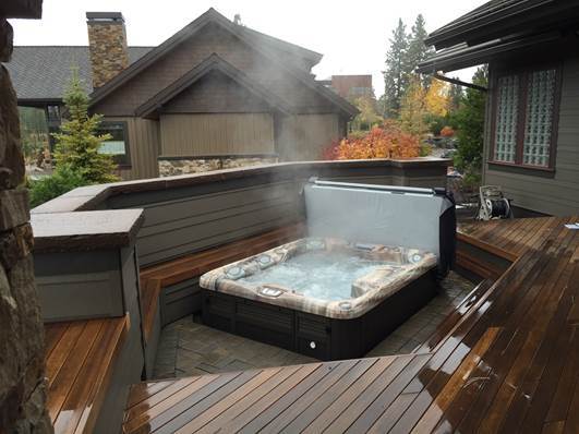 A relaxing hot tub with cover on a deck surrounded by autumn scenery.