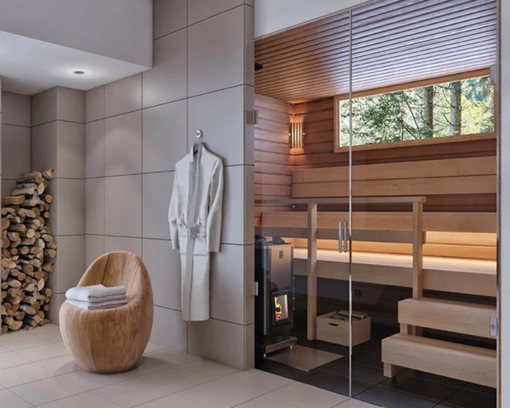 A modern sauna room with a glass door, featuring a wooden bench and a chair with towels