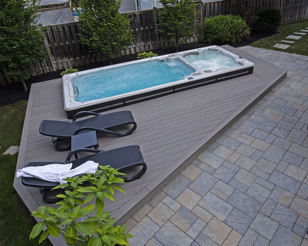 outdoor swim spa with crystal clear water, surrounded by a modern wooden deck and comfortable loungers
